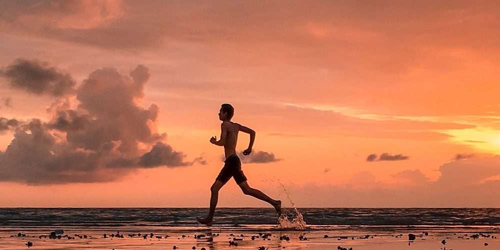 Un ragazzo corre e si allena accanto al mare: un buon modo per consumare energie e rimanere in forma