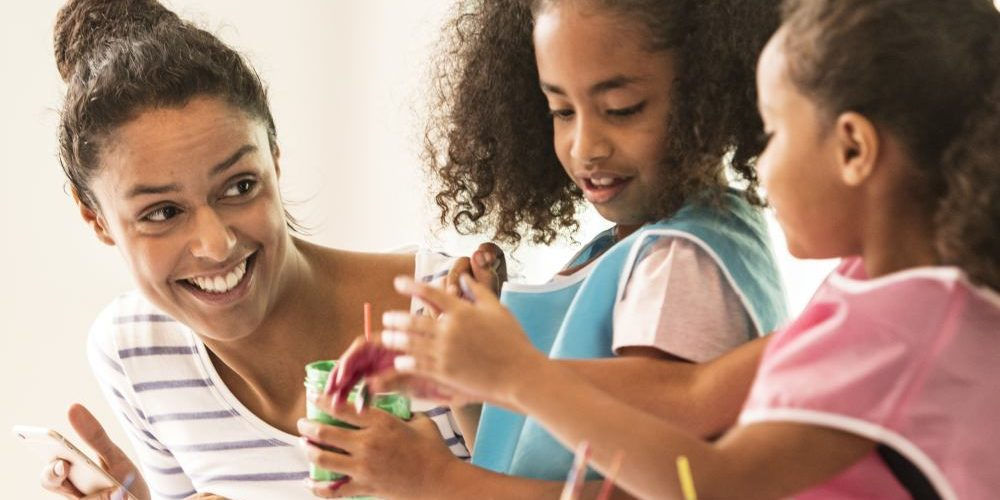 Una mamma e due bambine fanno dei lavori natalizi con materiali di riciclo