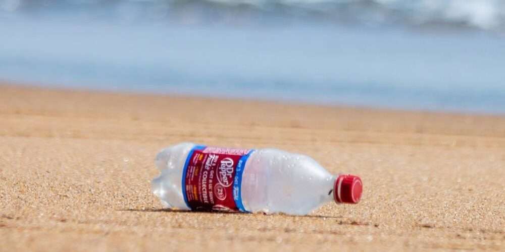 Bottiglia di plastica su una battigia: la plastica è uno dei rifiuti più comuni al mare secondo Legambiente