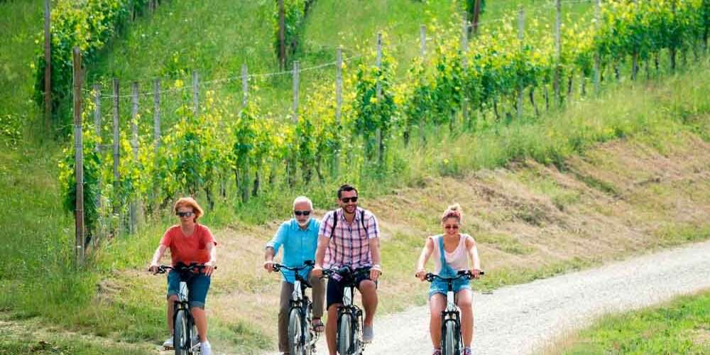 Un gruppo di ciclisti nel verde di una strada collinare italiana segue un itinerario per il cicloturismo