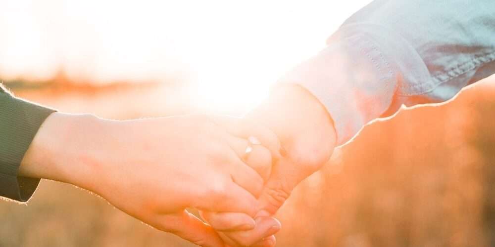 Primo piano di una mano femminile e una maschile che si tengono: anche i diritti umani sono fondamentali per la sostenibilità