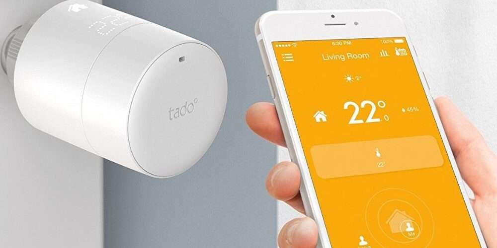 Primo piano di uno smartphone connesso a una valvola termostatica per il controllo della temperatura