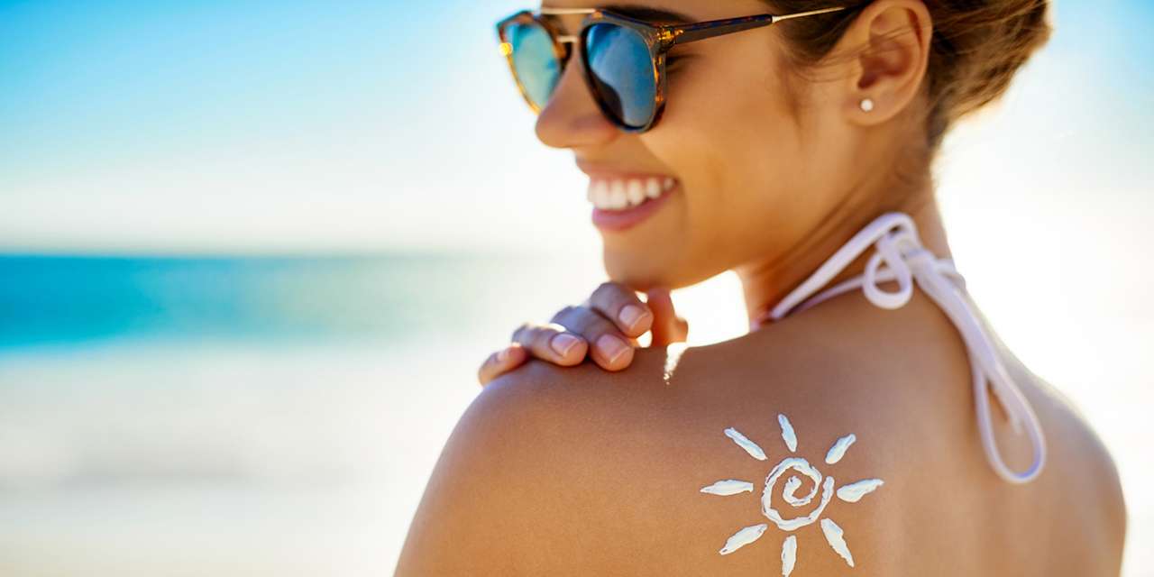 Una ragazza sorride su una spiaggia: le creme solari ecosostenibili sono le migliori