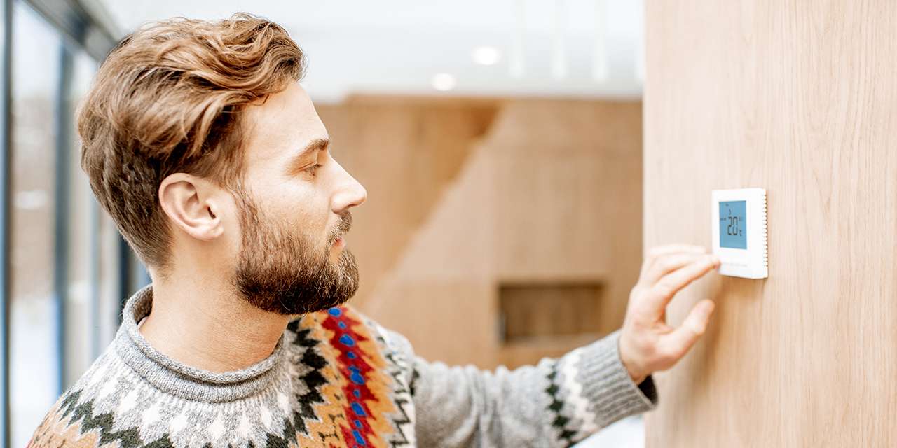 Un ragazzo sta impostando su un display la temperatura ideale per la casa