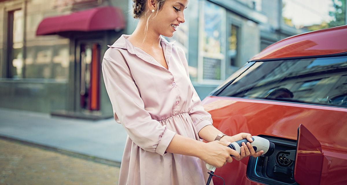 Una ragazza ricarica l’auto elettrica: la mobilità sostenibile è fondamentale per una vera transizione energetica