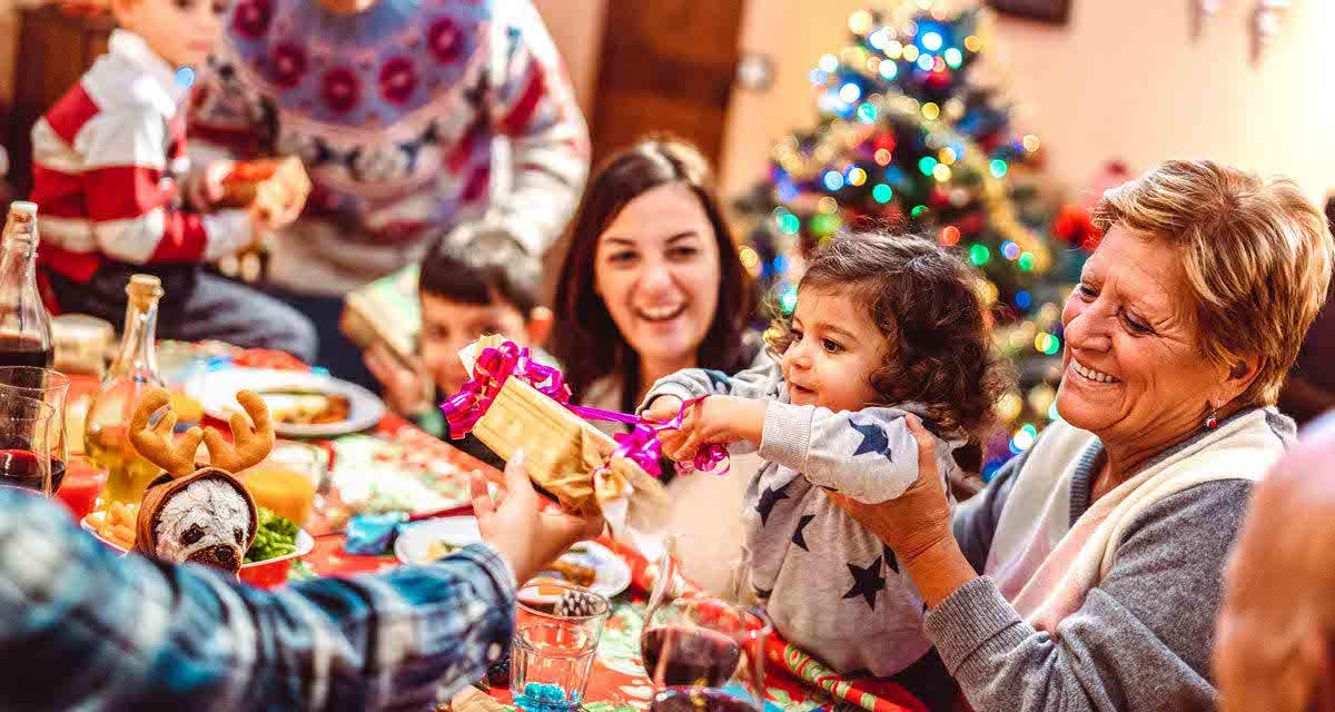 Una nonna con i nipoti scarta regali a Natale, un periodo perfetto per conciliare calore della famiglia e comportamenti responsabili come il riciclo 