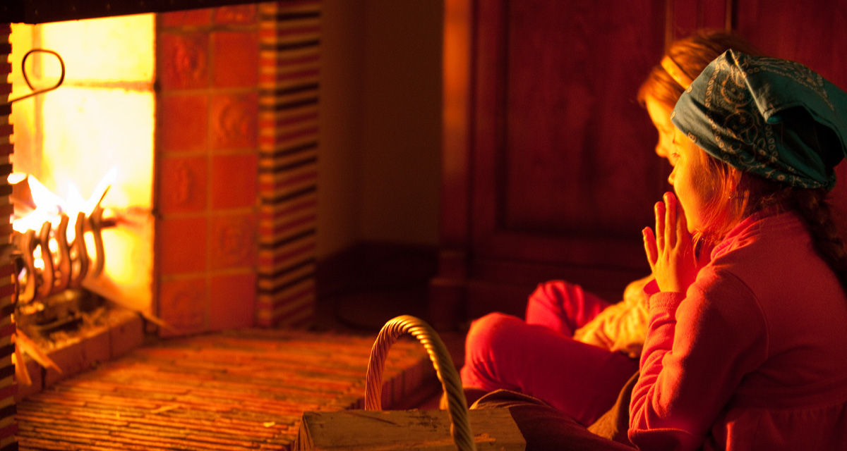 Due ragazze davanti a un camino, una fonte di calore per il riscaldamento nel passato