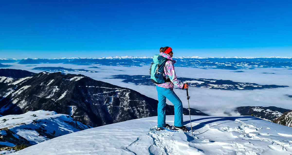 Una ragazza sulla neve in cima a una montagna riscopre i panorami e i boschi