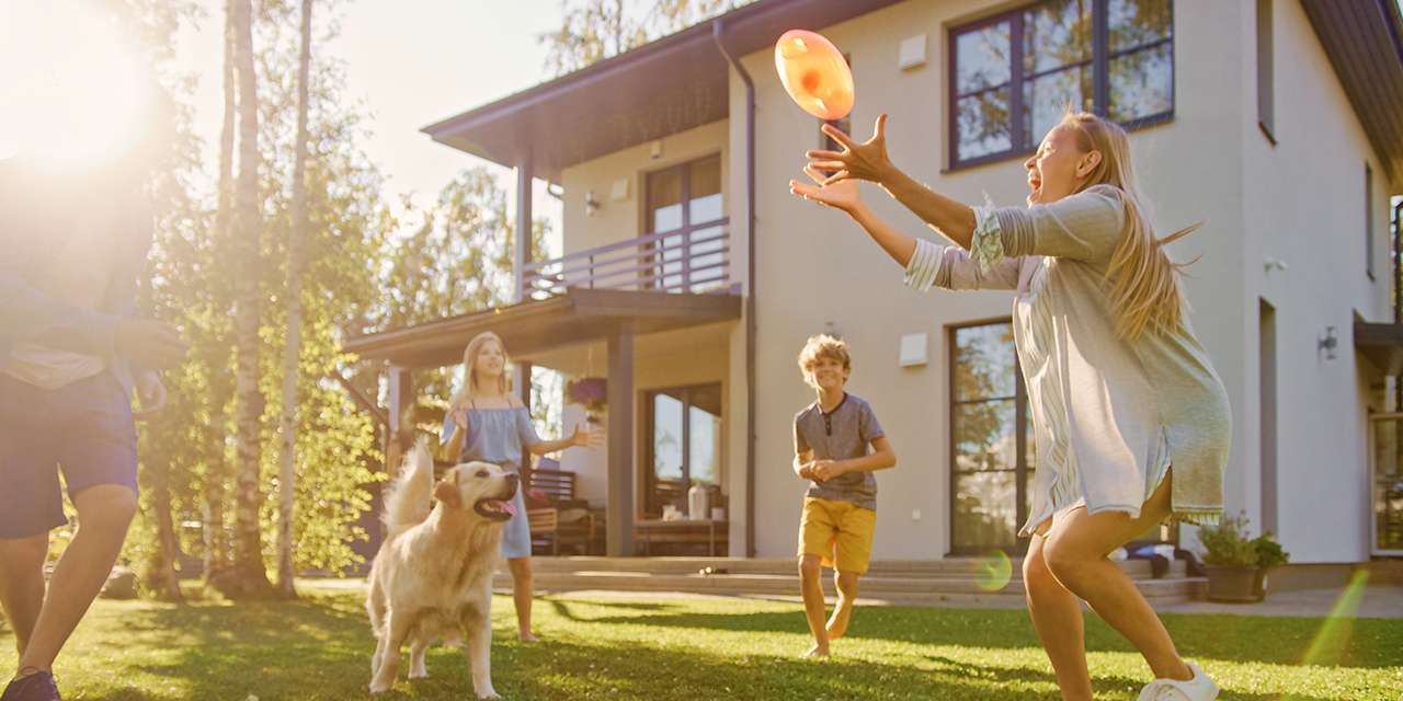 Una famiglia gioca su un prato accanto alla propria villetta indipendente