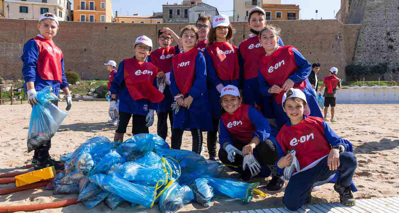 Bambini su una spiaggia con rifiuti raccolti per il progetto educativo E.ON Odiamo gli Sprechi