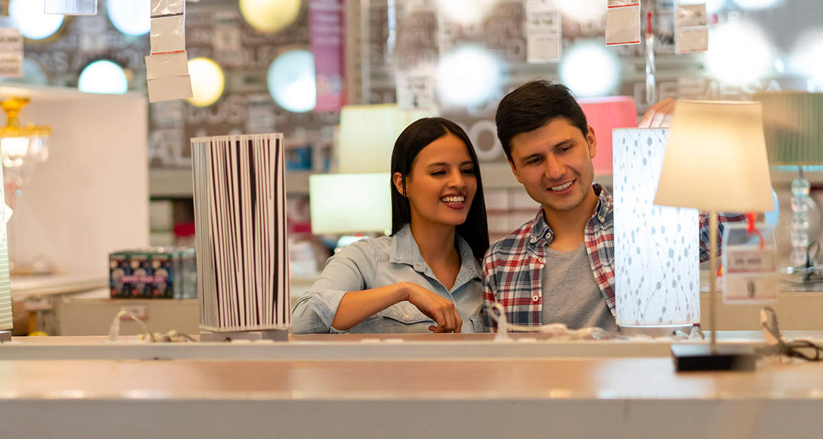 Una coppia sorridente valuta una lampada in un reparto luci di un negozio