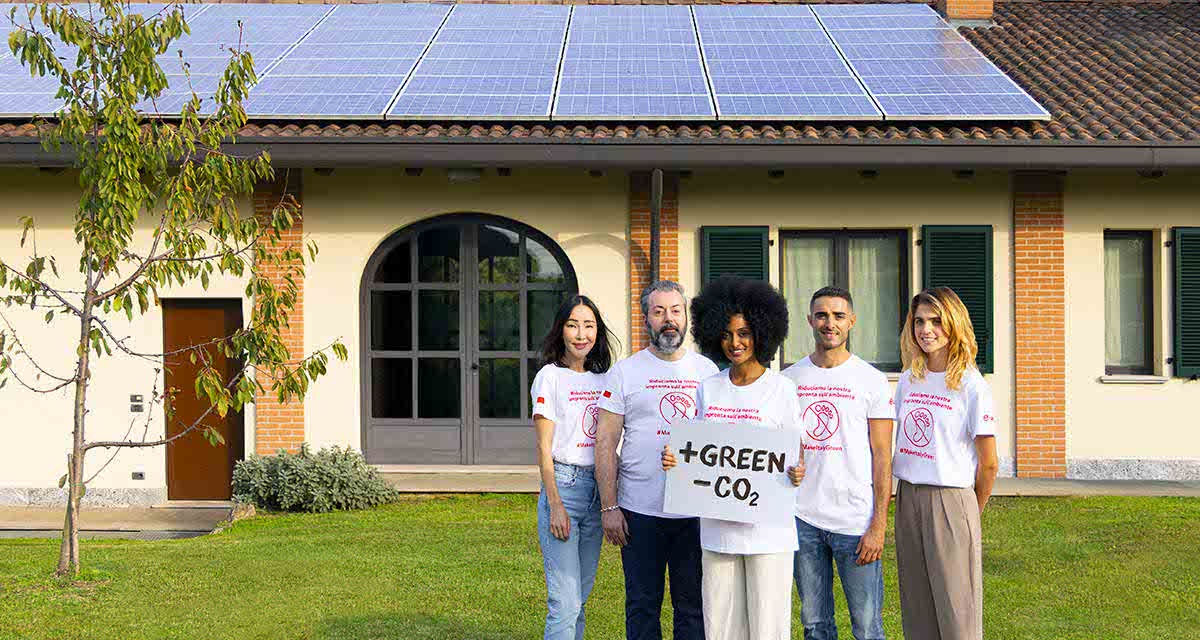 Ragazzi su un prato davanti a una grande casa con pannelli fotovoltaici