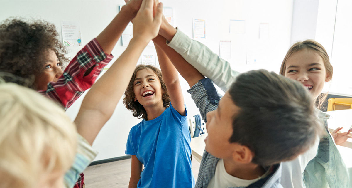 Dei ragazzi battono il cinque soddisfatti e sorridenti all’interno di una classe: le discipline STEM sono sempre più importanti per il futuro del Pianeta