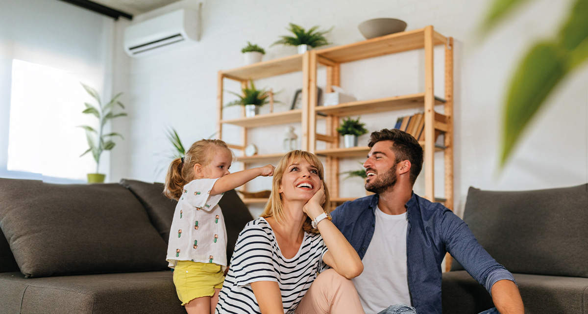 Una famiglia composta da una donna, un uomo e una bambina si divertono tra loro sul divano della loro casa