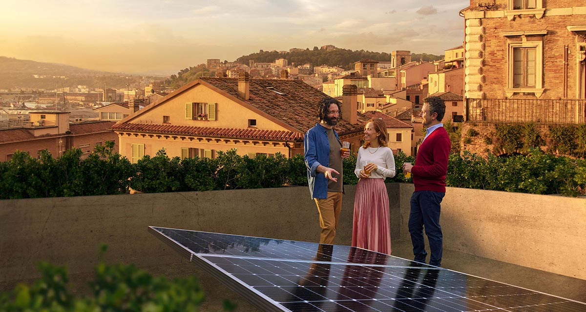 Un gruppo di amici parlano sorridenti accanto a un impianto fotovoltaico