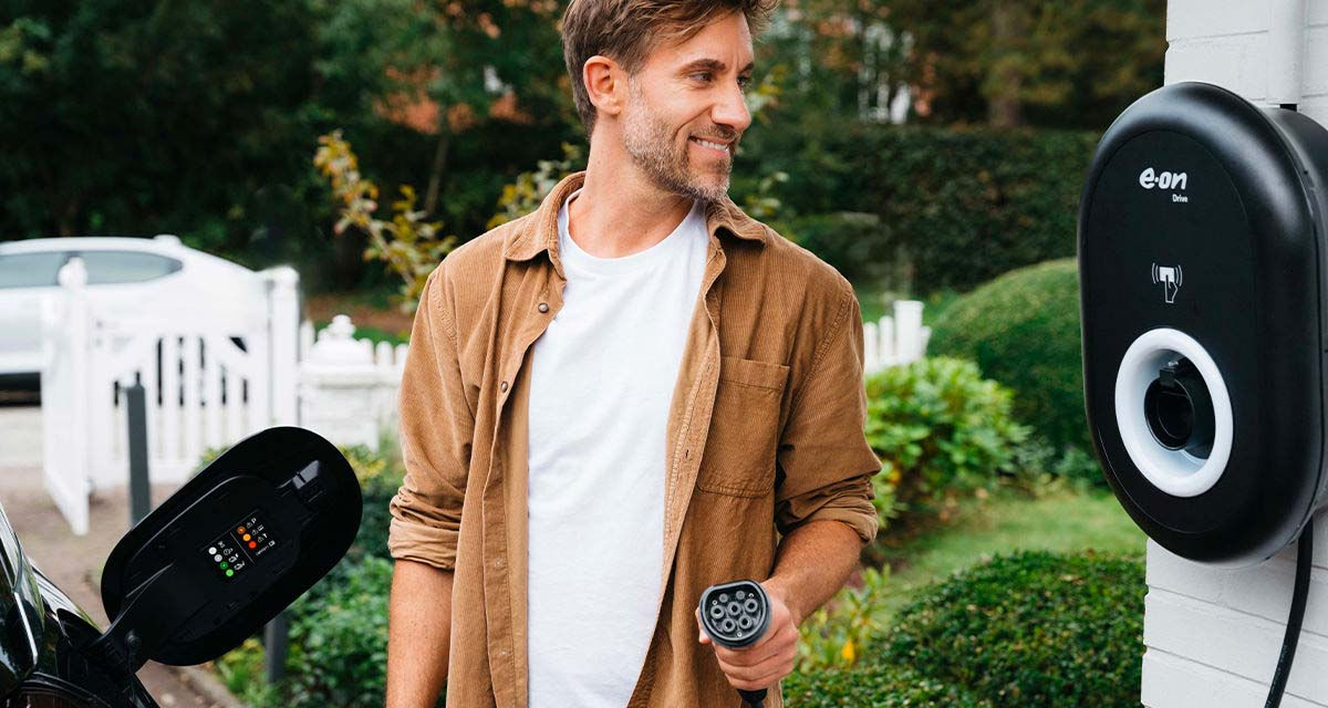 Un giovane uomo controlla la colonnina di ricarica domestica mentre sta per ricaricare la propria auto