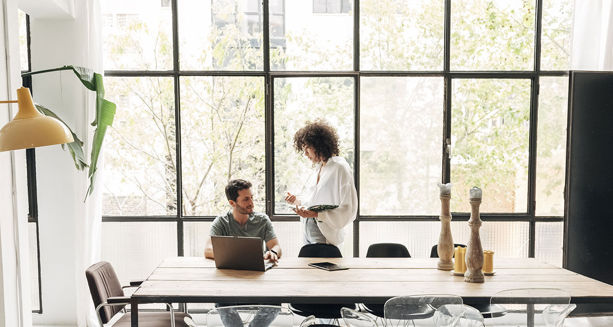 Un uomo e una donna, due giovani professionisti, in un soggiorno luminoso: chi lavora da casa può sfruttare le detrazioni fiscali per le utenze