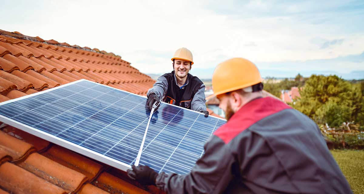 Tecnici al lavoro su un tetto con pannelli fotovoltaici: gli impianti fotovoltaici sono incentivati da detrazioni fiscali e contributi a fondo perduto 