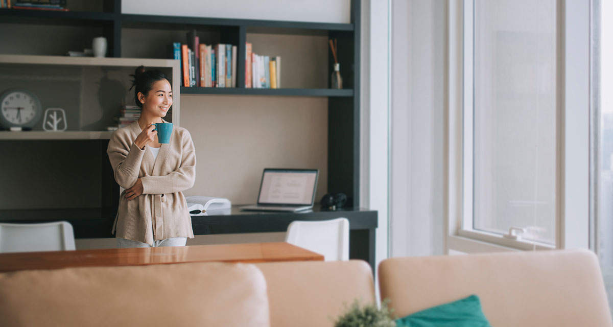 Una giovane donna si rilassa in un soggiorno con ampie vetrate e un climatizzatore ad alta efficienza